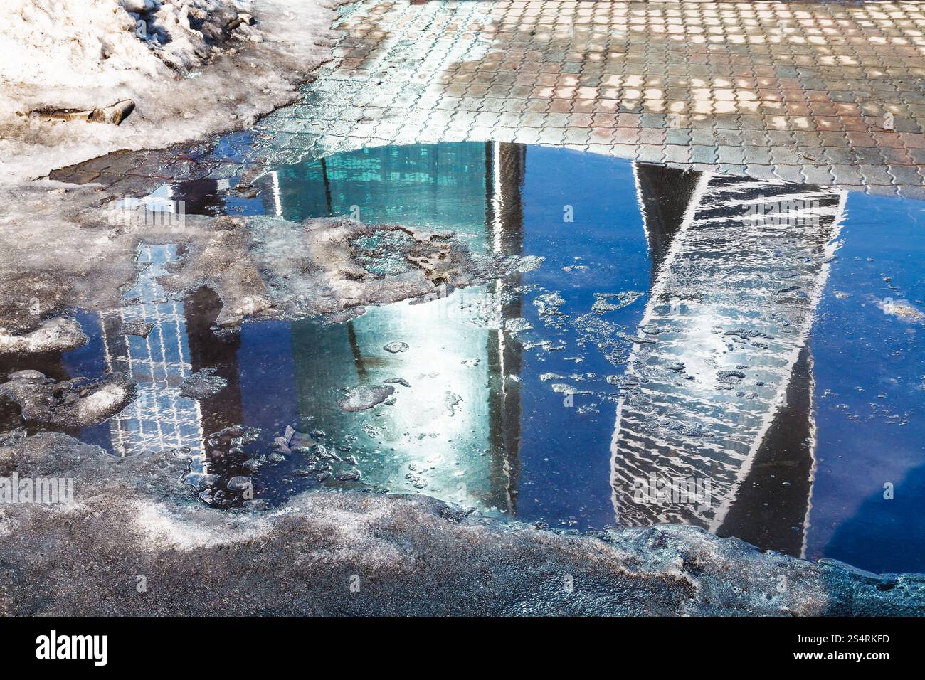 La molla del paesaggio urbano con fusione della neve pozza e casa riflessione nella città di Mosca Foto Stock
