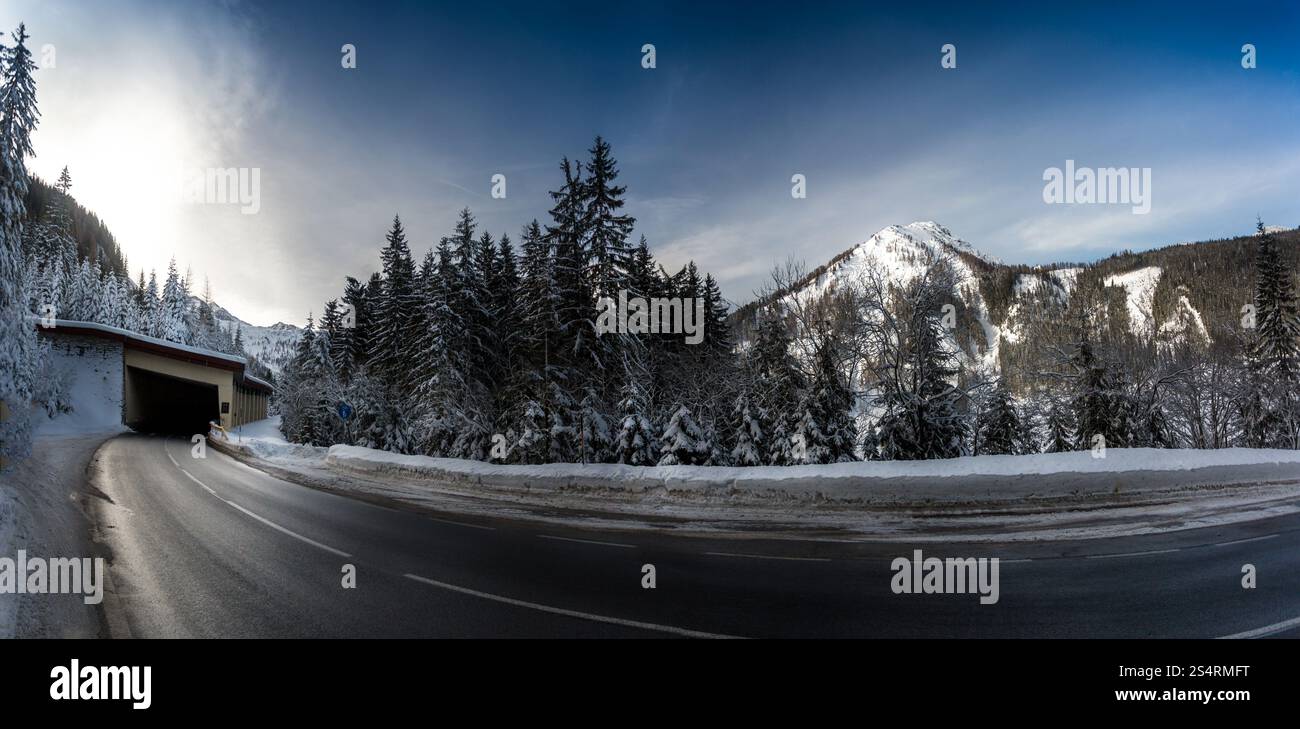 Bellissimo scatto panoramico di autostrada in montagne innevate con un lungo giro Foto Stock