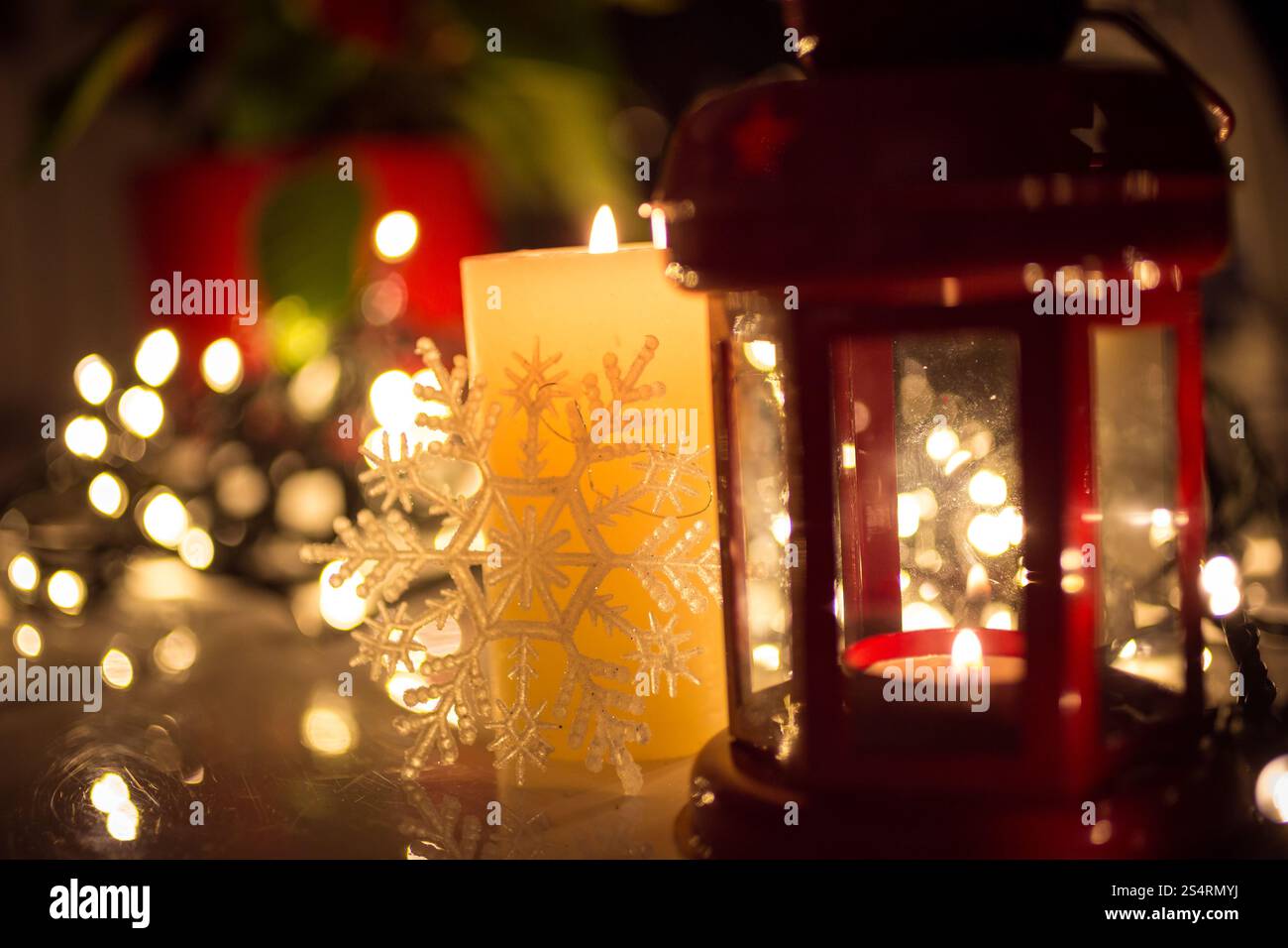 Primo piano di luci di Natale, candela che brucia e lanterna vintage sul tavolo Foto Stock