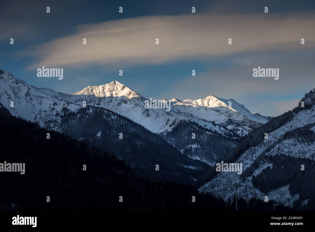 Bellissimo paesaggio del sole che splende sulla cima della montagna coperta di neve Foto Stock