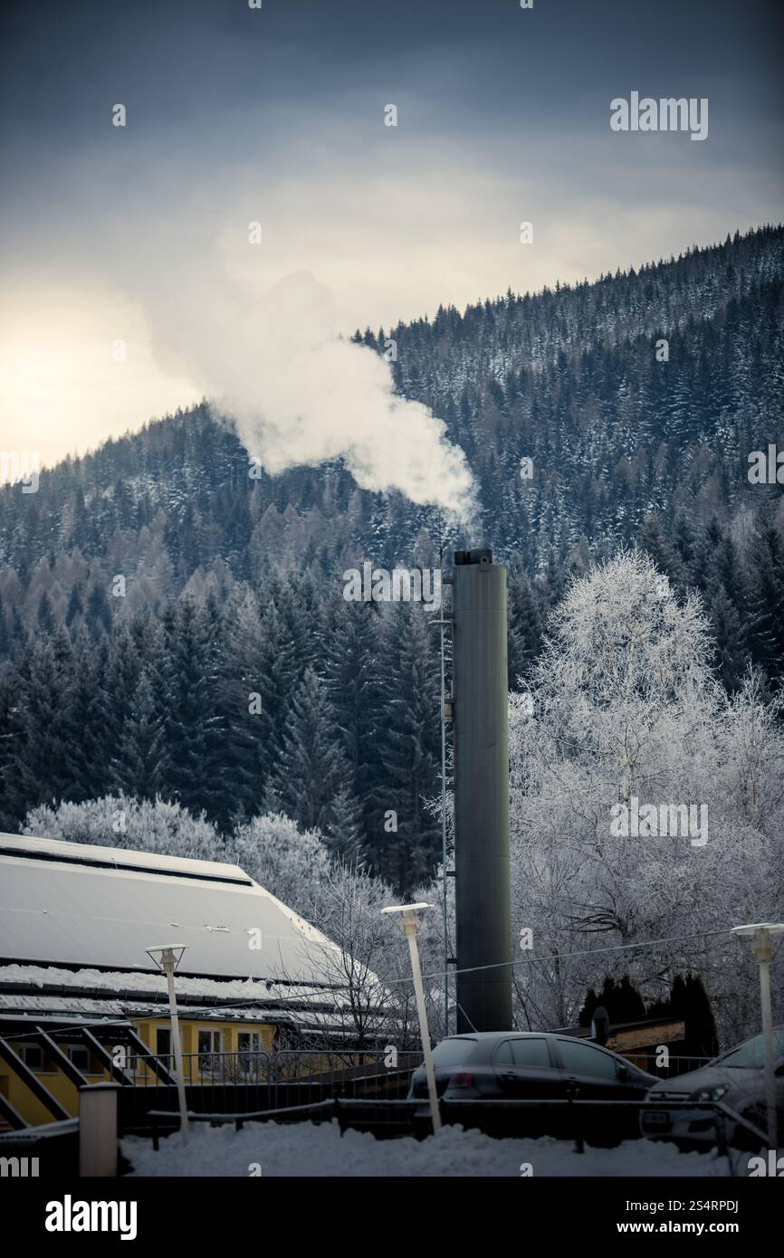 Piccola fabbrica con tubo di vapore nelle Alpi innevate al giorno Foto Stock