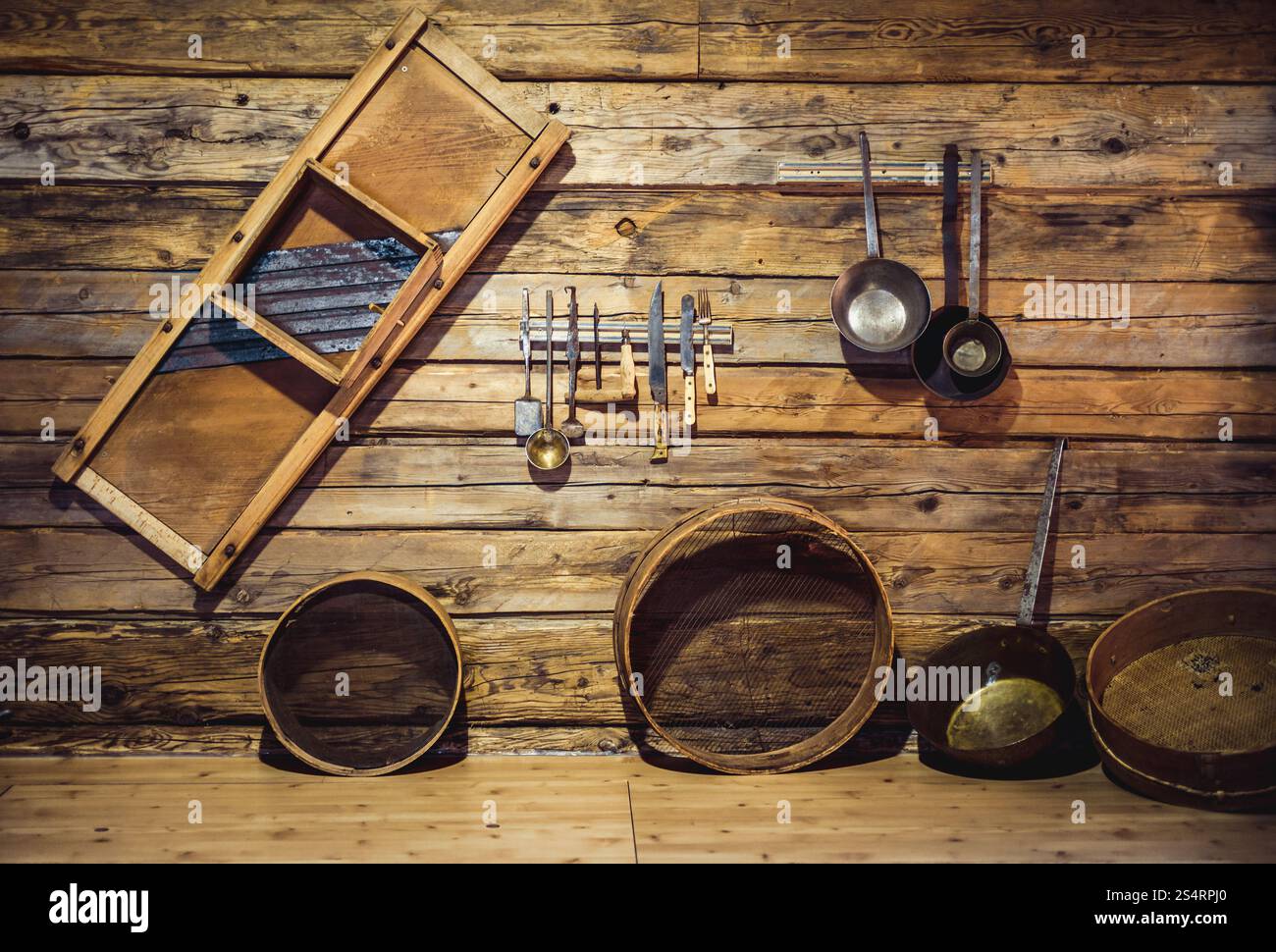 Primo piano della vecchia utensili tradizionali appeso alla parete di legno in cucina Foto Stock