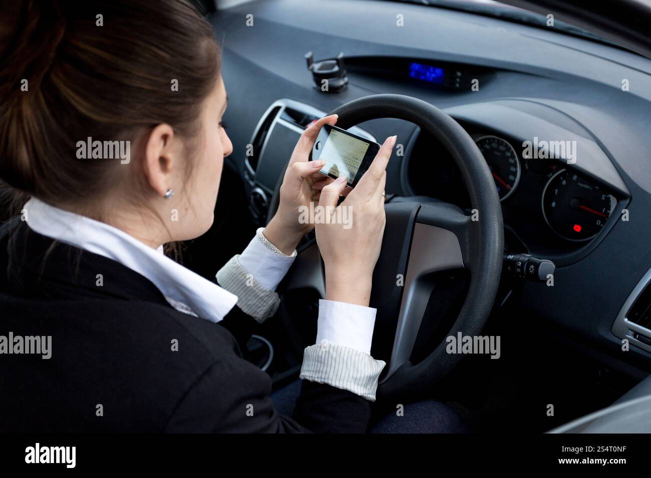 Giovane imprenditrice utilizza lo smartphone durante la guida auto Foto Stock