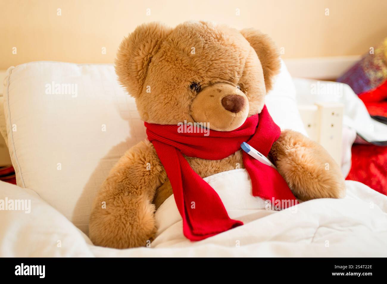 Primo piano di marrone Teddy bear in leggere sciarpa giacente in letto con termometro Foto Stock