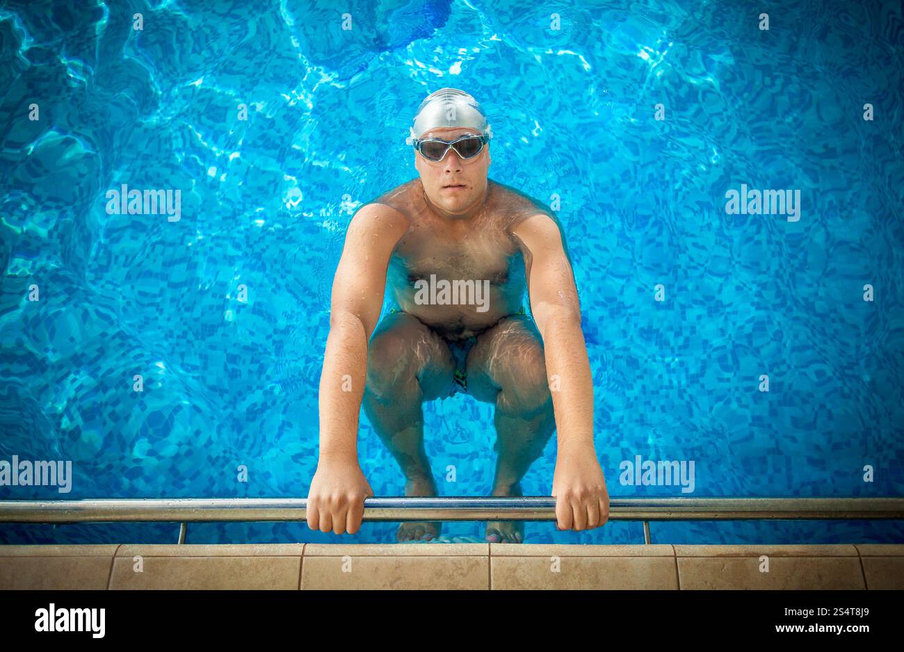 Giovane atleta maschio di trattenimento sul bordo della piscina e la preparazione di nuotare Foto Stock