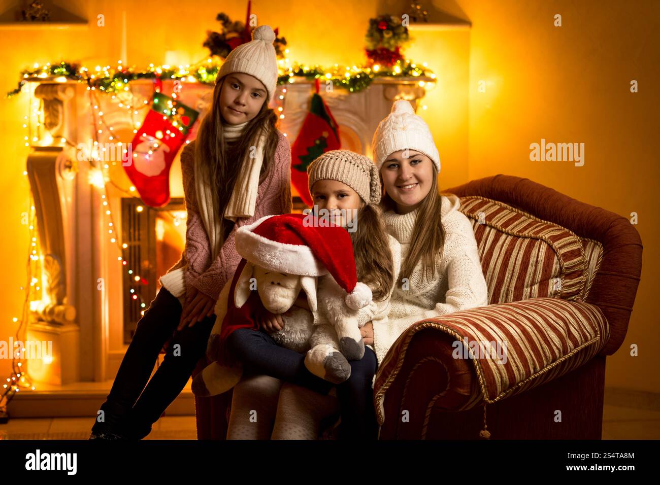 Bellissimo ritratto di famiglia contro il camino alla vigilia di Natale a casa Foto Stock