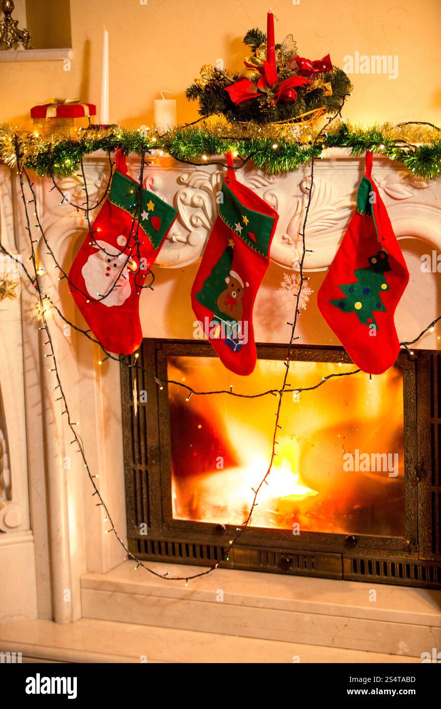 Ingrandimento di foto di interni di tre calze di Natale appeso sul camino decorato Foto Stock