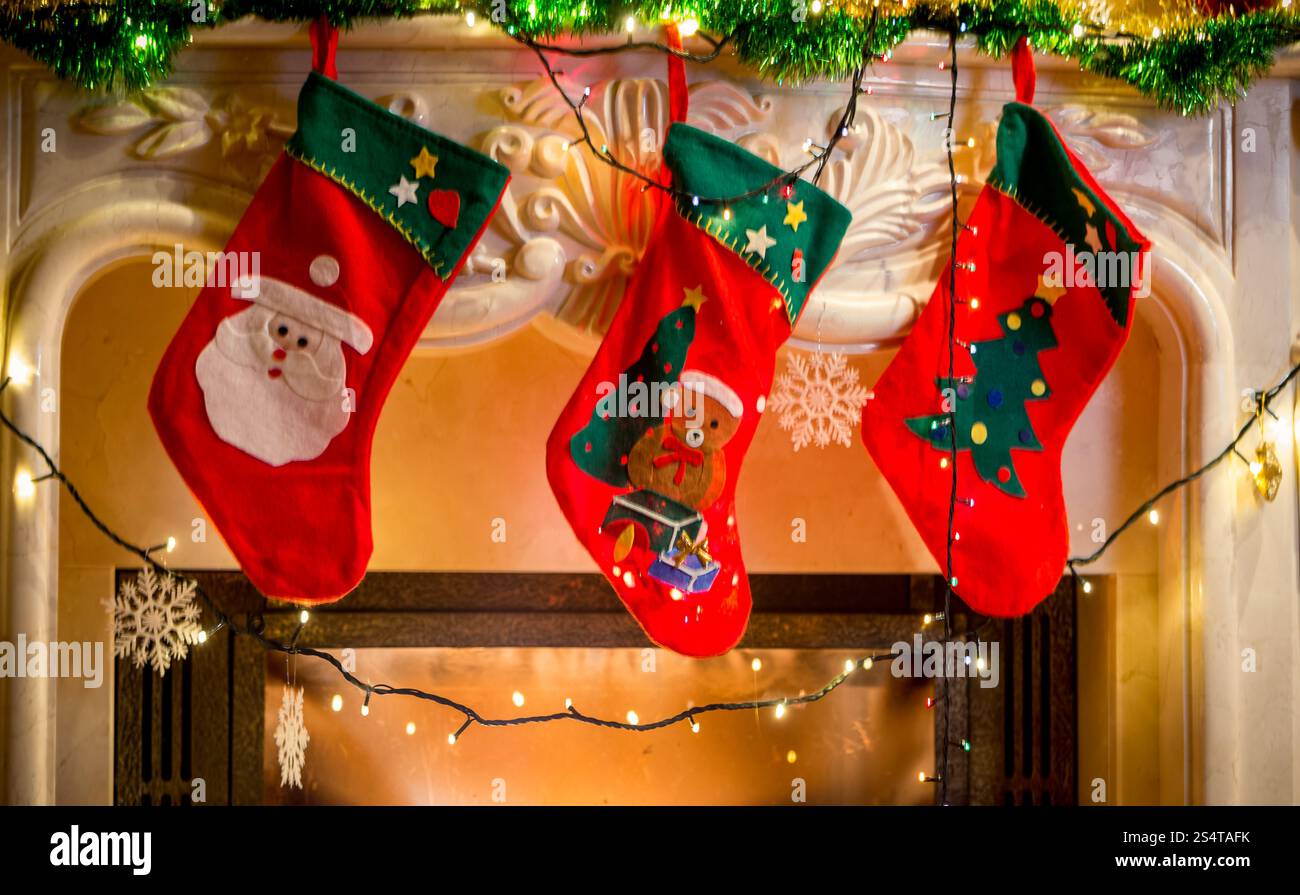 Tre rosso calze di Natale appeso sul camino decorato Foto Stock