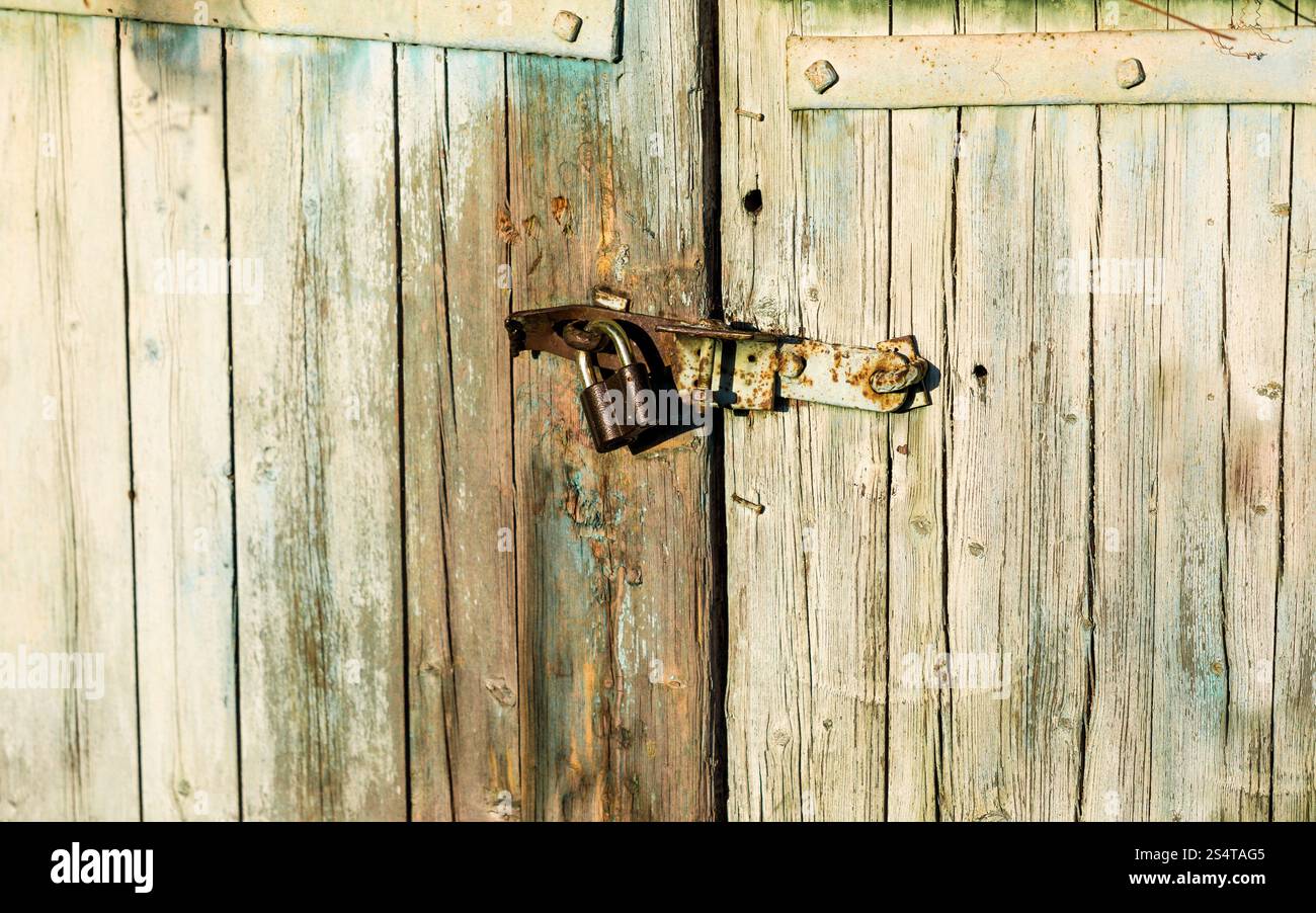 Primo piano della vecchia serratura metallica appeso sul legno della porta del granaio Foto Stock