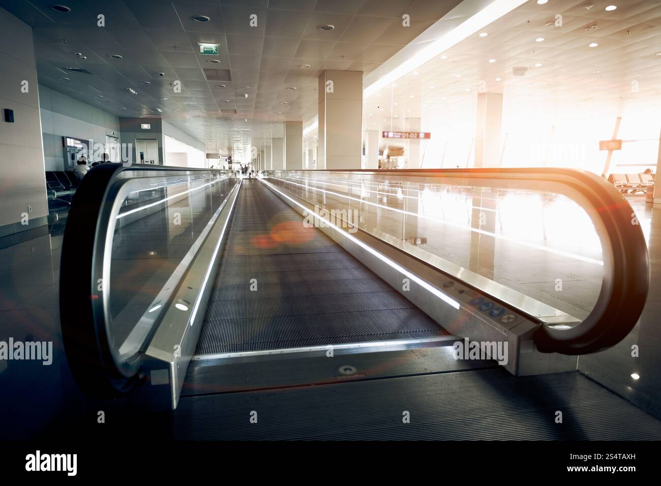 Orizzontale lungo la scala mobile al moderno aeroporto terminale in corrispondenza della luce del sole Foto Stock