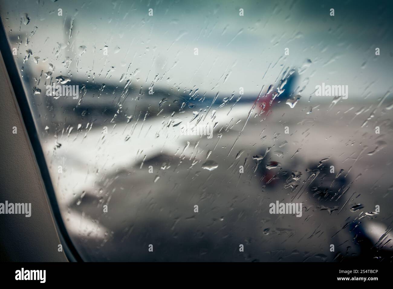Vista sfocati sull'ala di aeroplano attraverso il vetro passeggero con gocce di pioggia Foto Stock