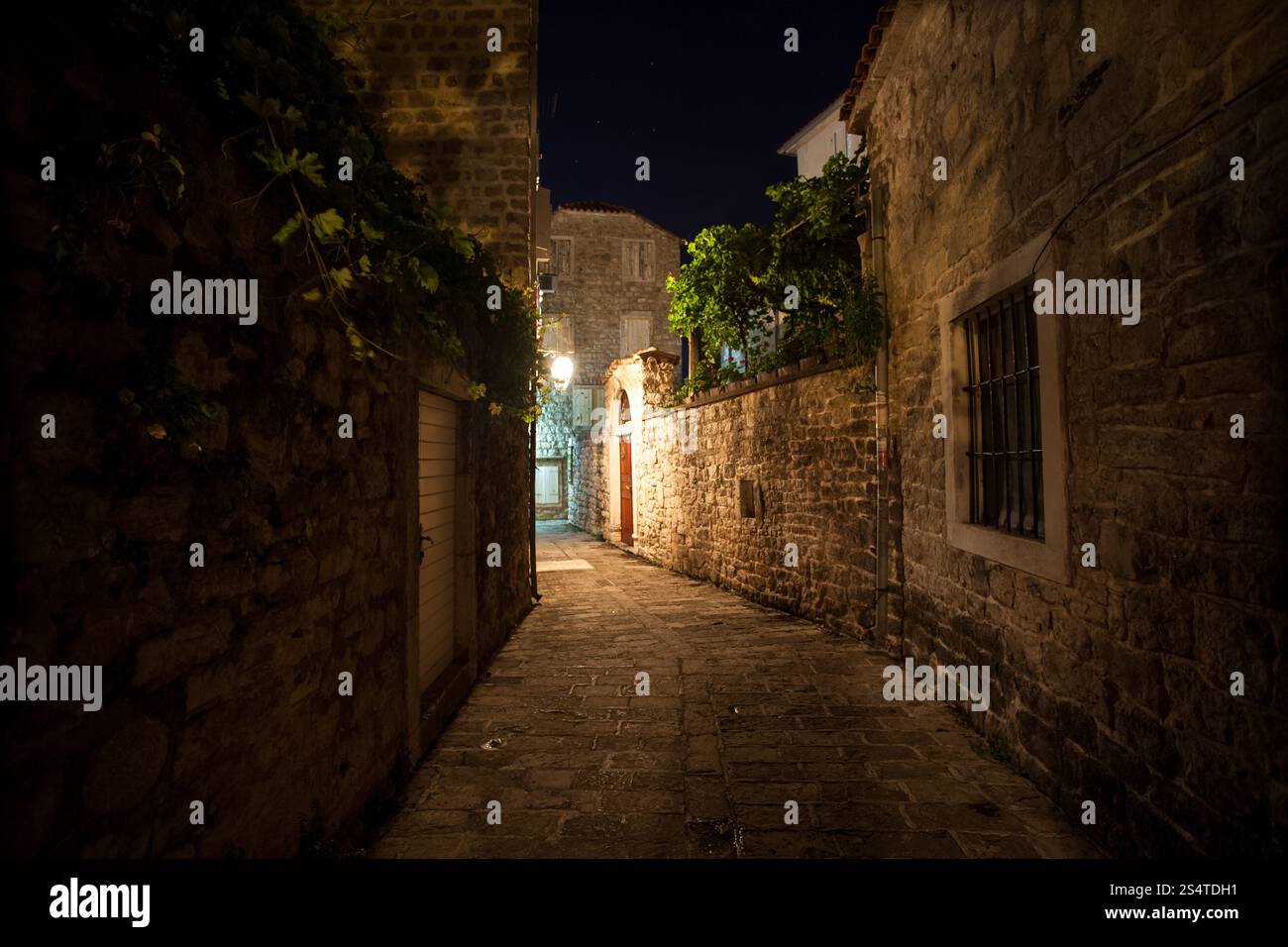 Lunga strada stretta e antica illuminato da lanterne a gas di notte Foto Stock