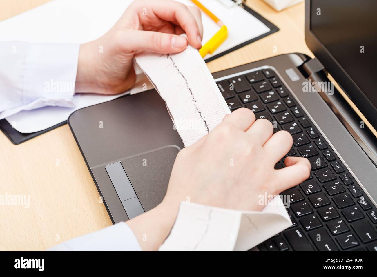 Medico esamina elettrocardiogramma del paziente con il computer portatile Foto Stock
