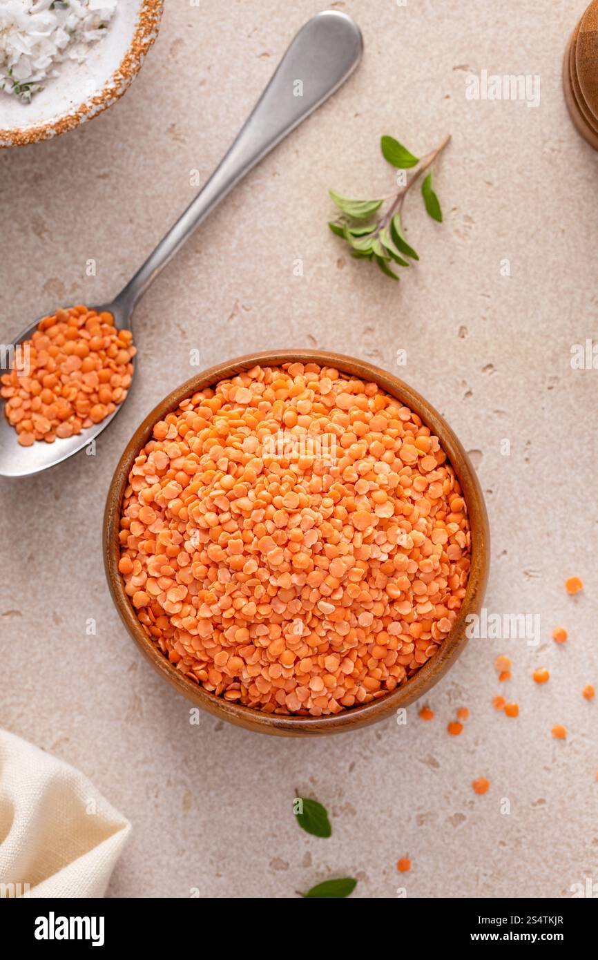 Lenticchie rosse secche pronte per essere cotte in una ciotola di legno, fonte di proteine vegane Foto Stock