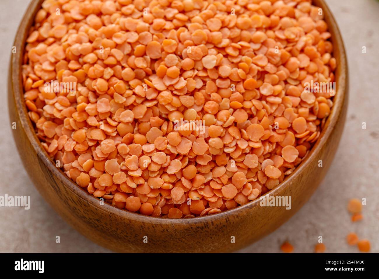 Lenticchie rosse secche pronte per essere cotte in una ciotola di legno, fonte di proteine vegane Foto Stock