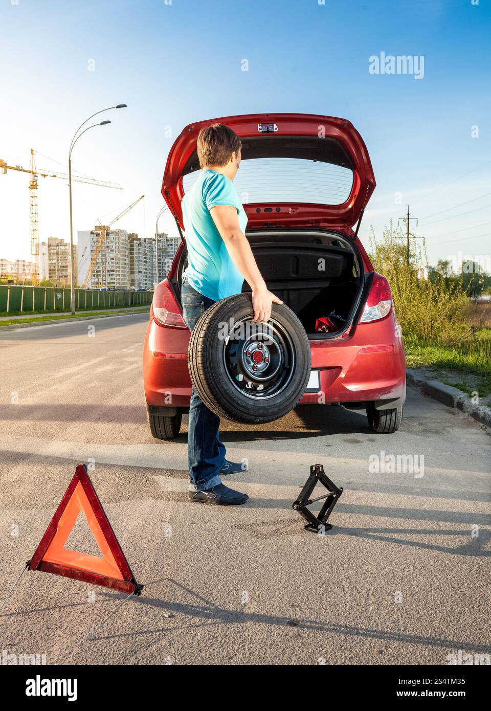 Foto di un uomo prendendo la ruota di scorta al di fuori del tronco Foto Stock