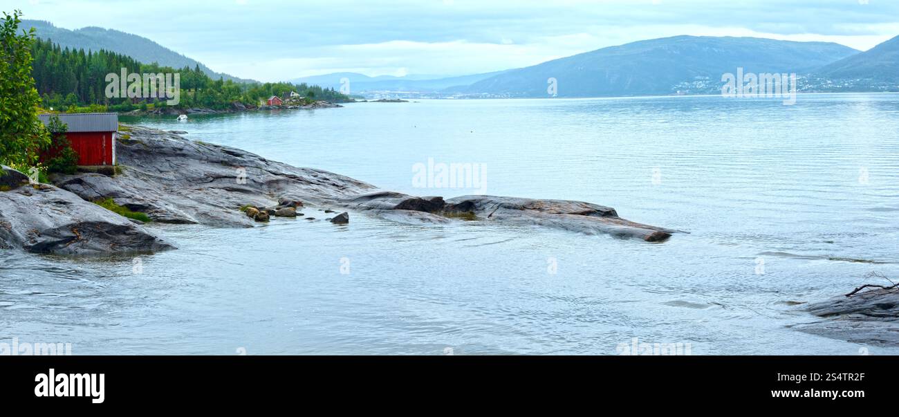 Fiordo vista nuvolosa estiva con casa in legno sulla costa (Norvegia) Foto Stock
