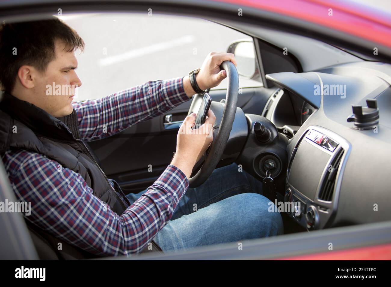 Ritratto di giovane uomo la digitazione di messaggi mentre si è alla guida di un veicolo Foto Stock