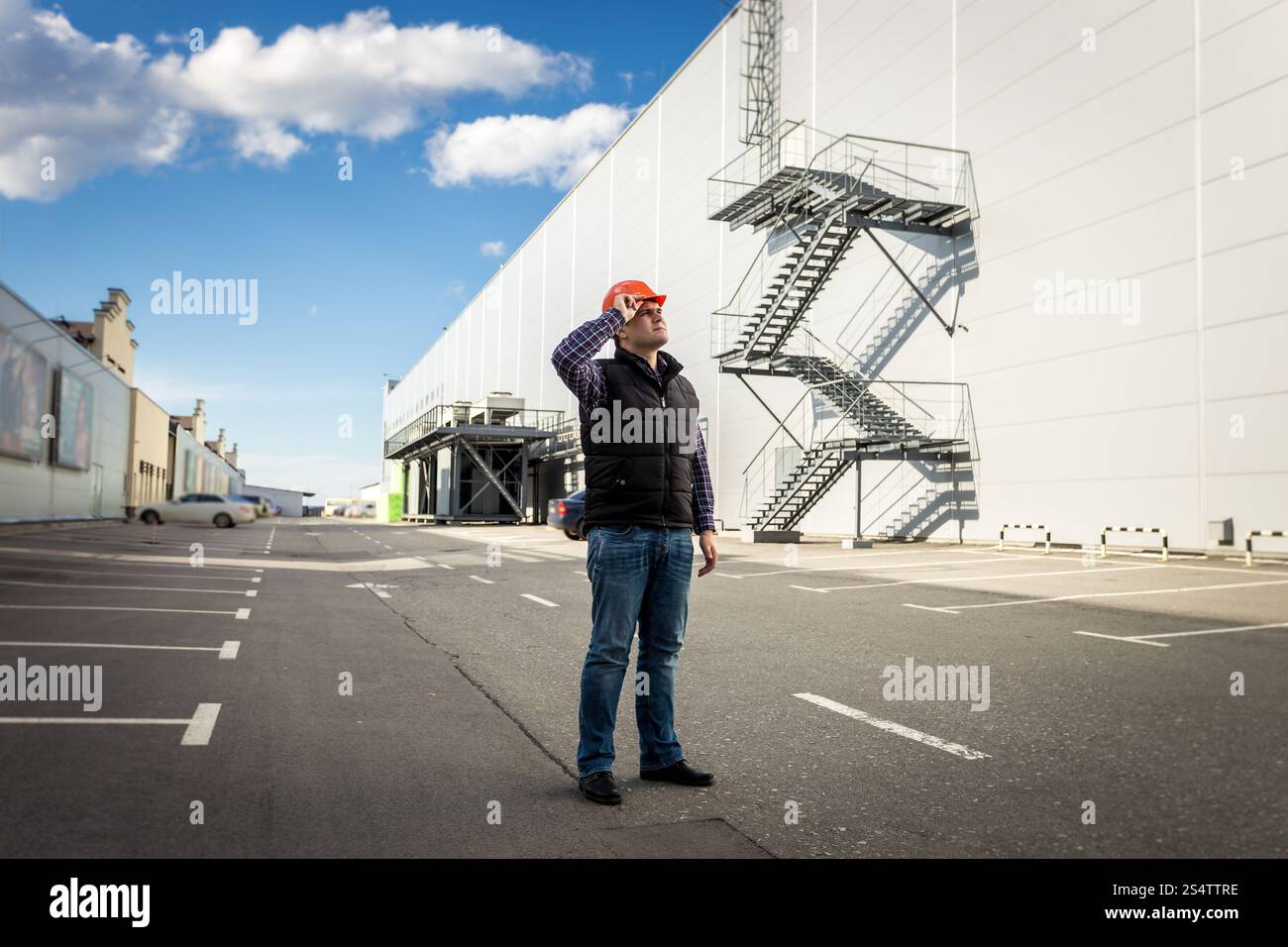 A piena lunghezza ritratto del lavoratore di sesso maschile in posa sul parcheggio di edilizia industriale Foto Stock