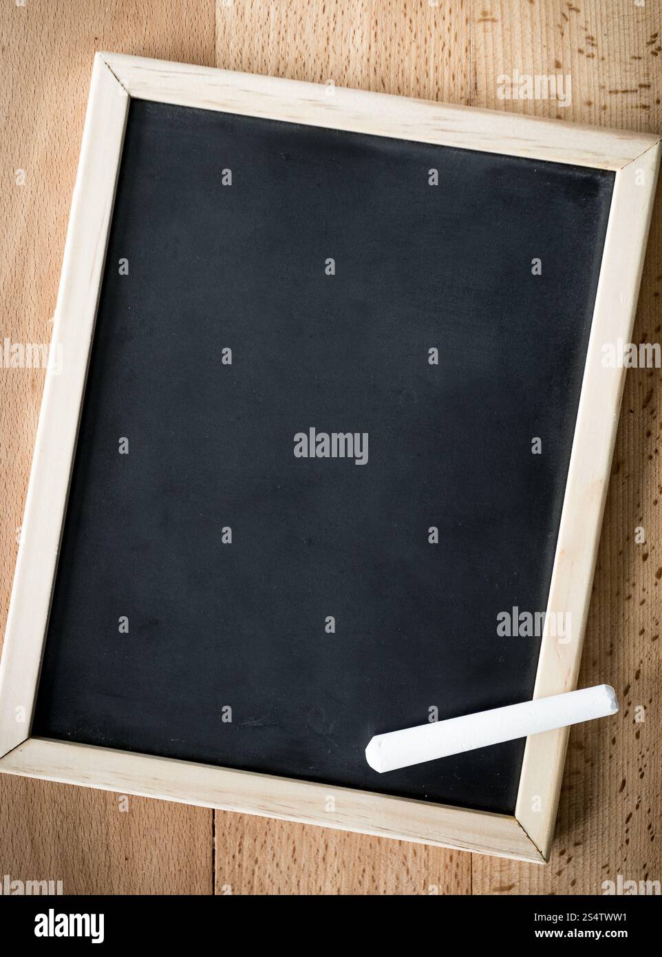 Closeup shot di gesso bianco giacente sulla lavagna nera su sfondo di legno Foto Stock