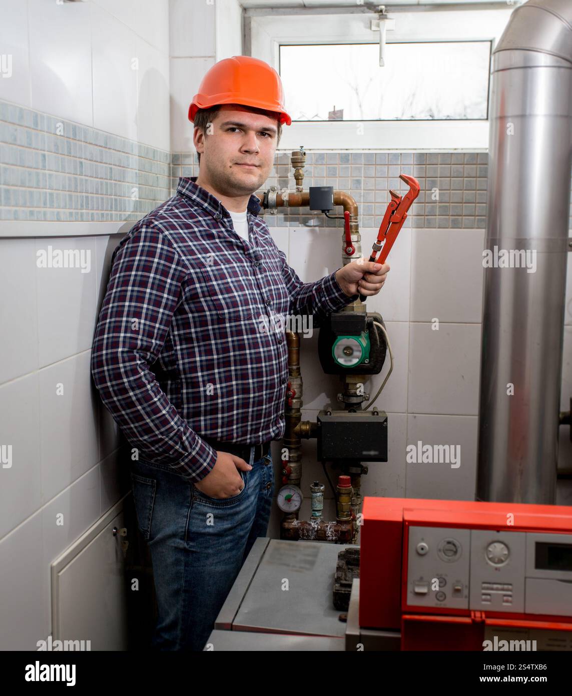 Ritratto di sorridere plumber in posa con pinze a sala caldaie Foto Stock