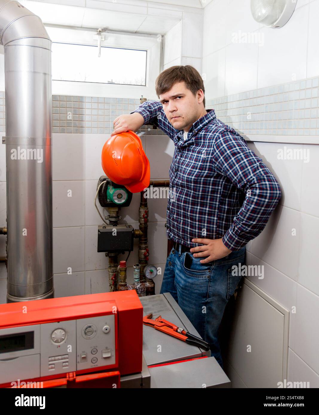 Professional confuso plumber guardando il complicato sistema di riscaldamento Foto Stock