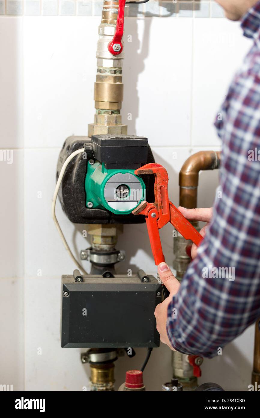 Closeup colpo di plumber riparazione impianto di riscaldamento con una pinza rossa Foto Stock