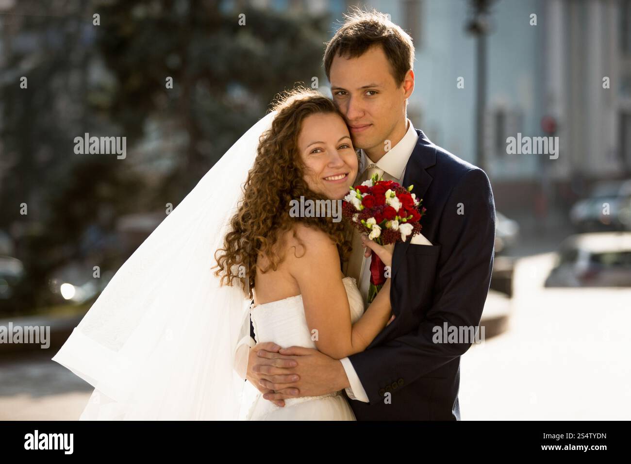 Ritratto di una coppia felice appena sposata che abbraccia per strada Foto Stock