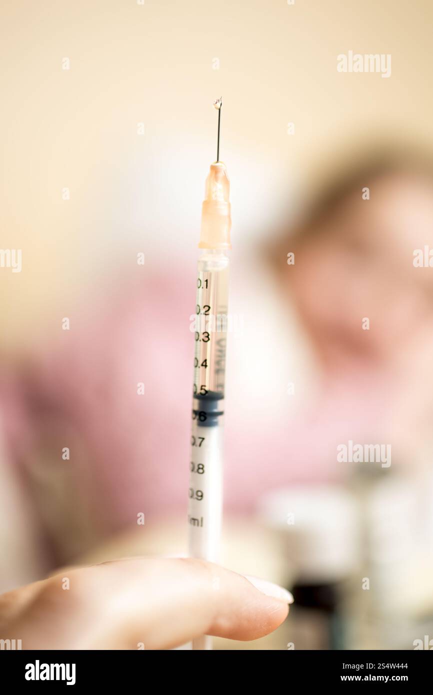 Foto macro di donna tenendo la siringa accanto al bambino malato a letto Foto Stock