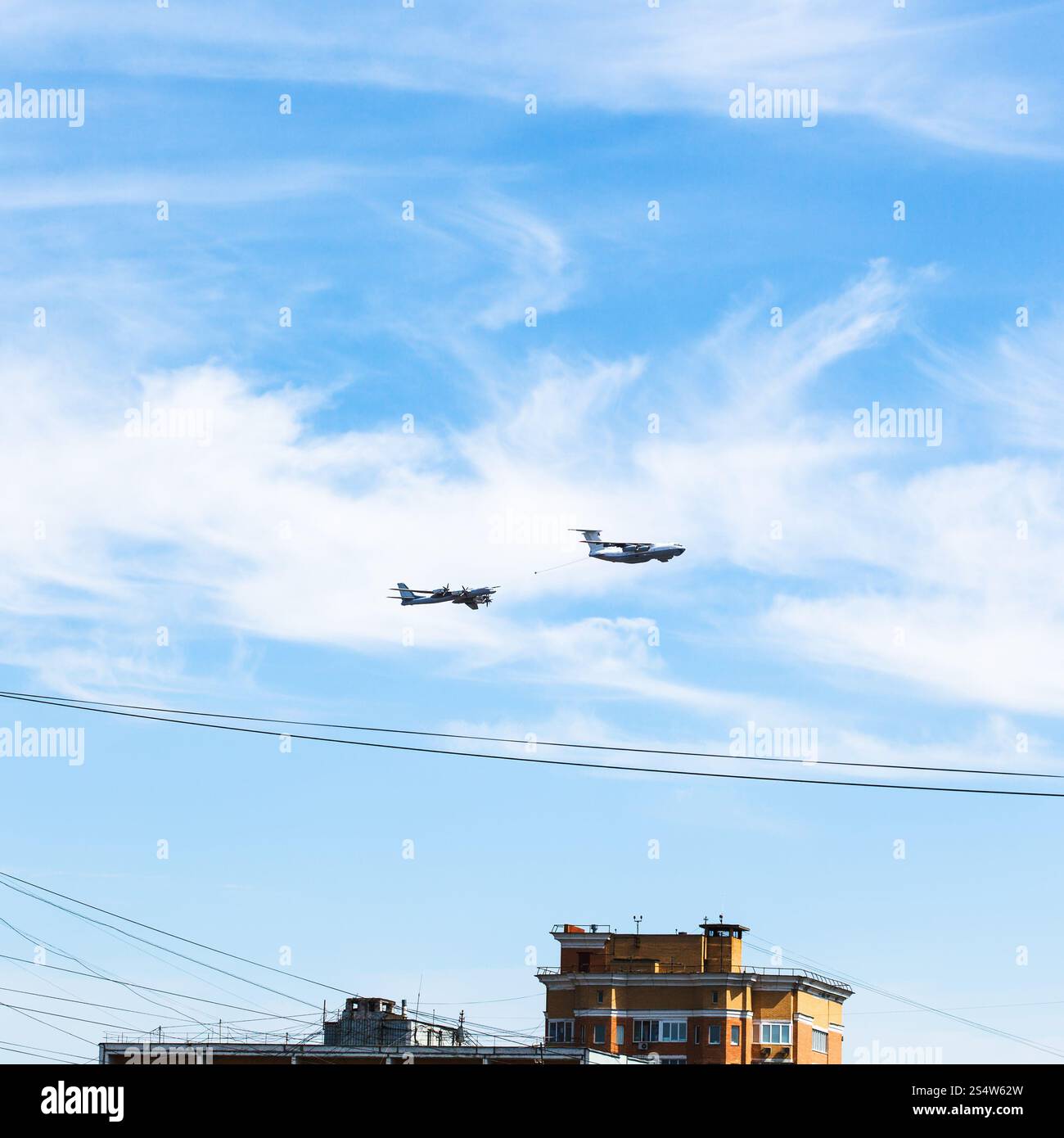 Il rifornimento di aria del bombardiere a turboelica aerei in cielo blu su casa urbana Foto Stock
