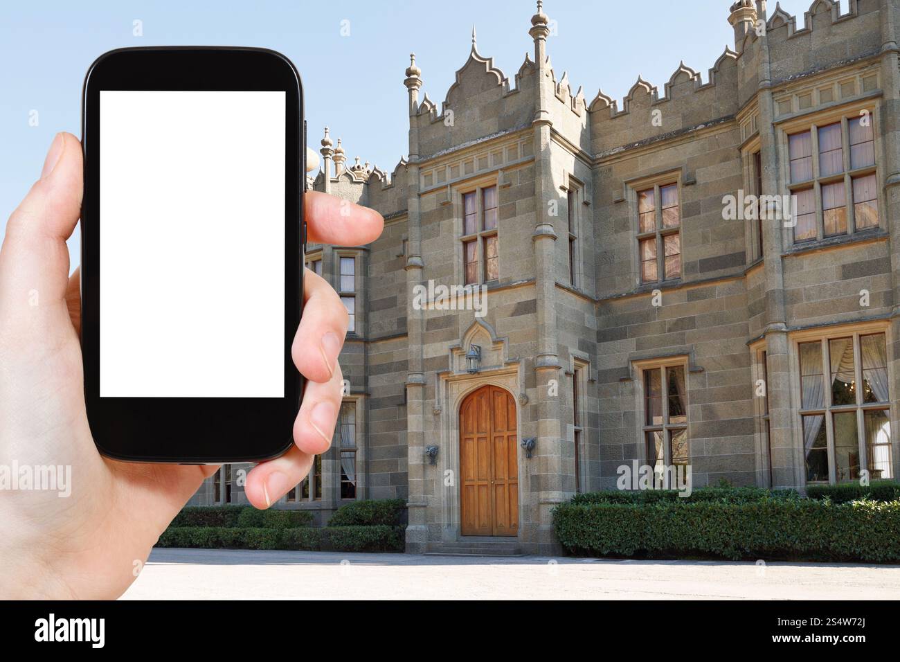 Concetto di viaggio - foto turistiche sulla facciata dell'ingresso nord del Palazzo Vorontsov (Alupka) in Crimea su smartphone con schermo ritagliato e vuoto Foto Stock