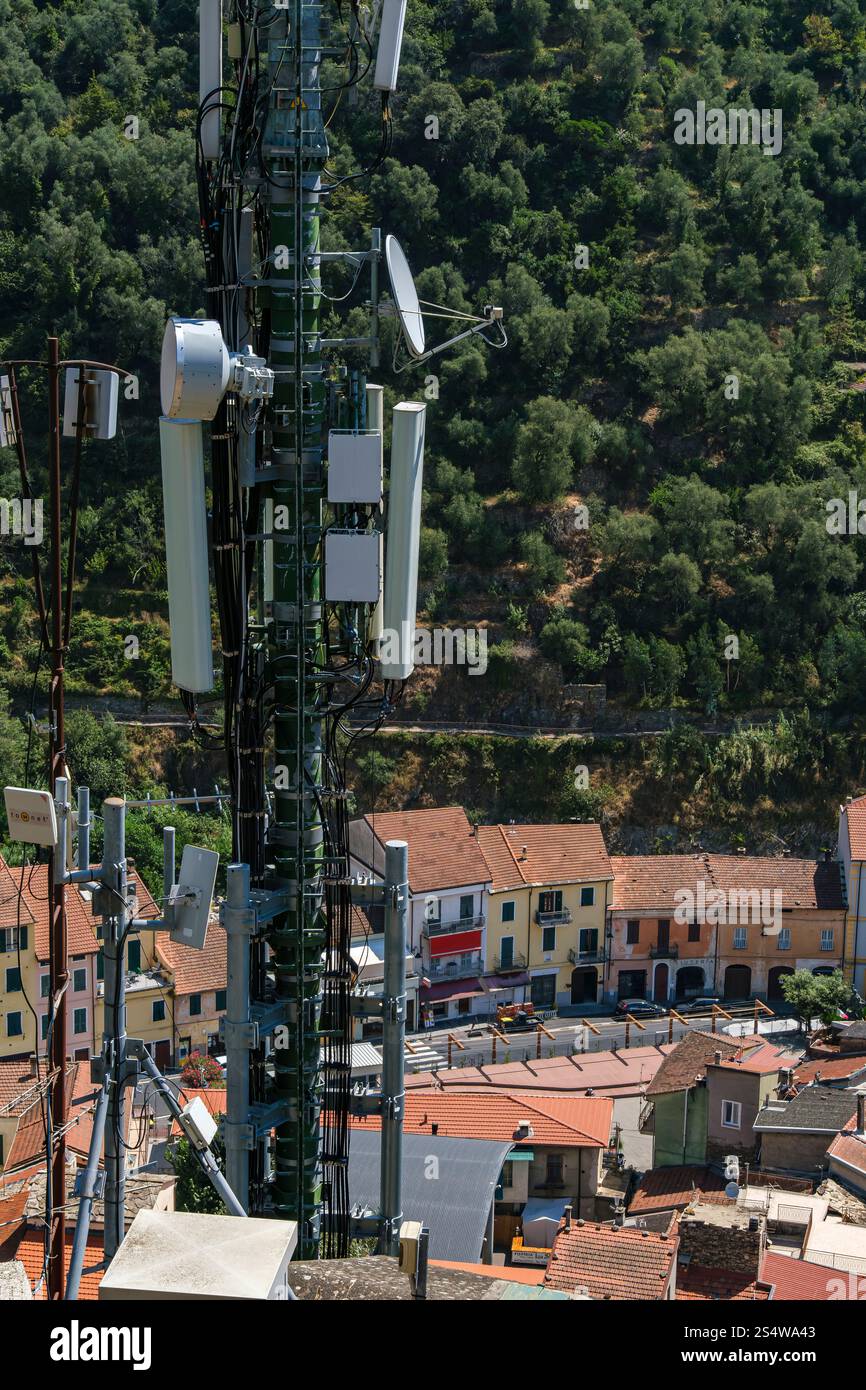 Albero di trasmissione e stazione di telefonia mobile con vista sul centro storico di Badalucco, provincia di Imperia, Liguria, Italia. Foto Stock