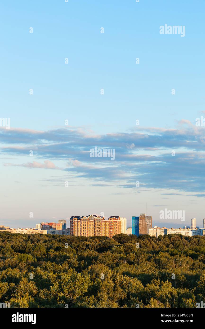 Cielo blu sulla città e la foresta verde in serata estiva Foto Stock