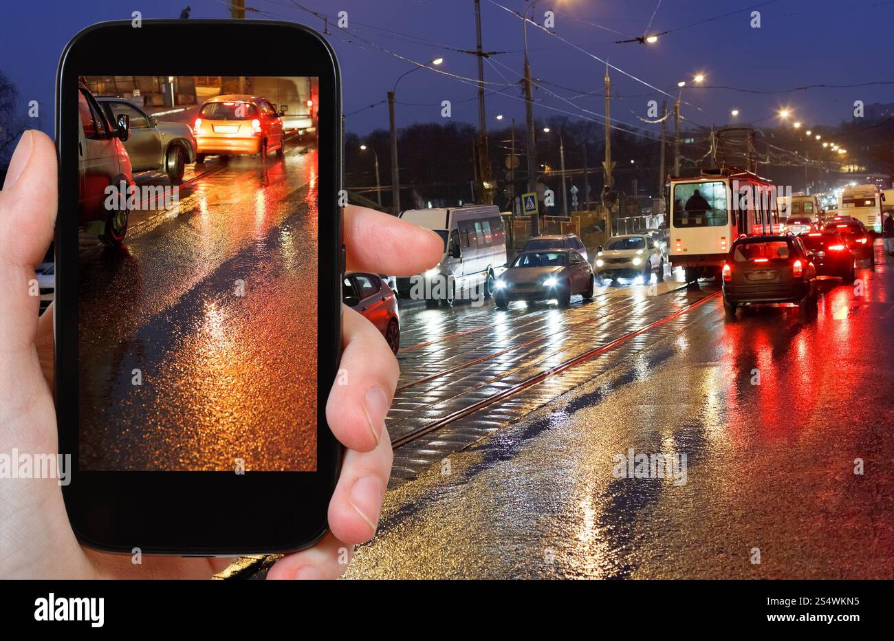concetto di viaggio - fotografie turistiche foto del traffico di auto notturne in piena pioggia sullo smartphone Foto Stock