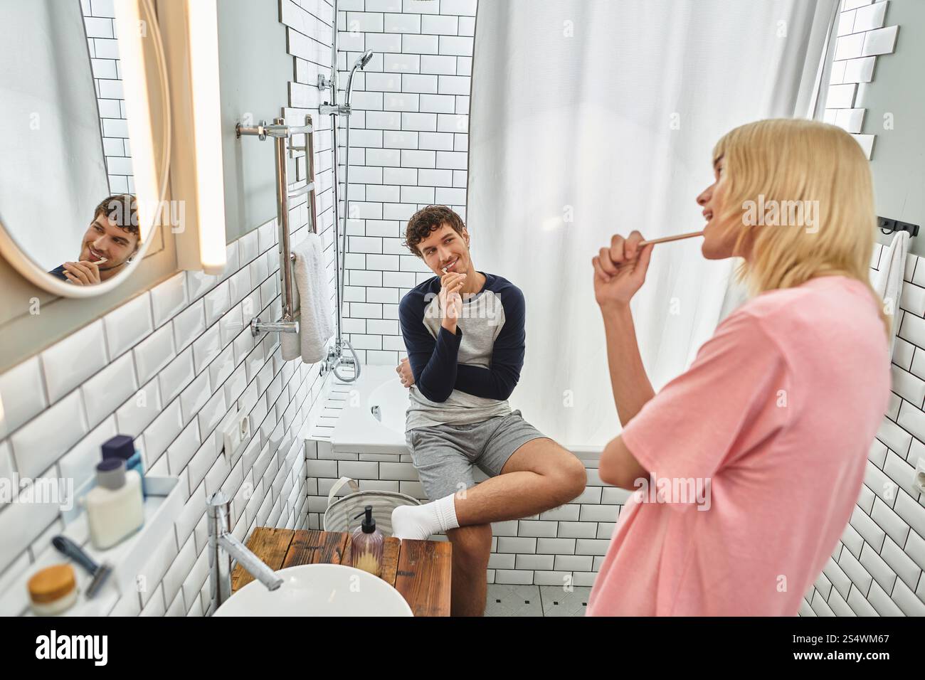 In un bagno accogliente, due uomini si godono una divertente routine mattutina, preparandosi per la giornata. Foto Stock