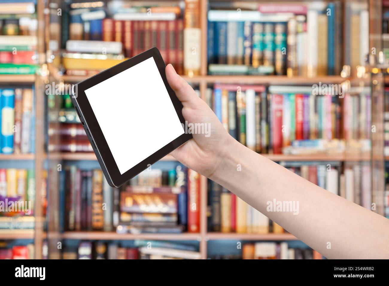 Mano trattiene un tablet pc con taglio fuori schermo e la libreria sullo sfondo Foto Stock