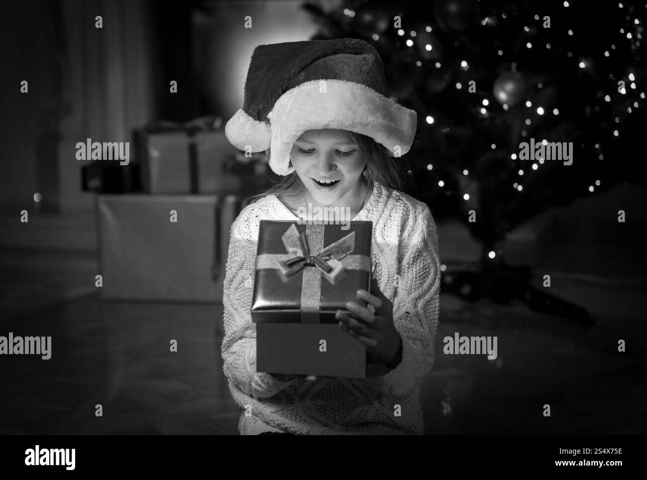 Ritratto in bianco e nero di felice sorpreso ragazza cerca all'interno del regalo di Natale Foto Stock