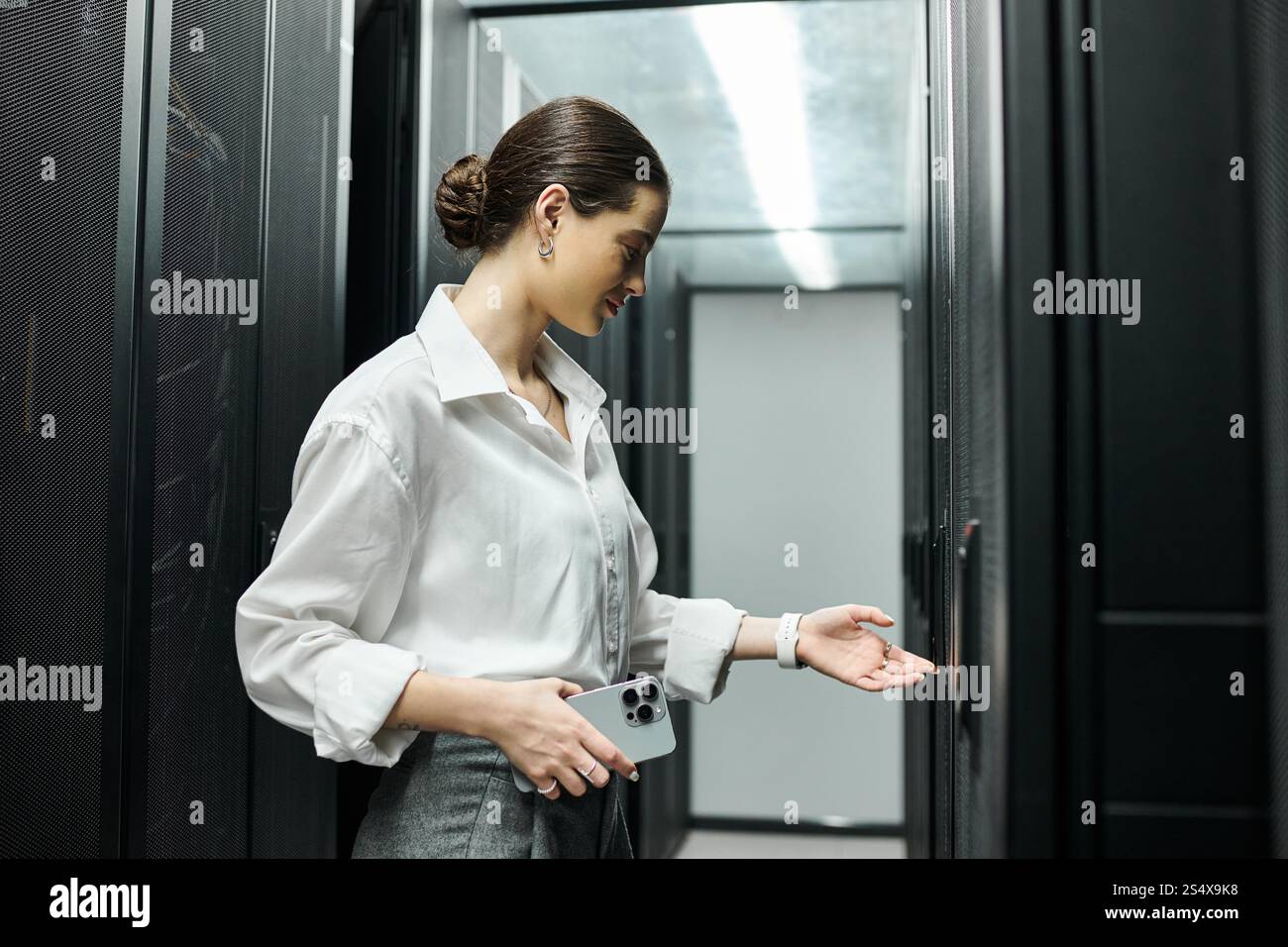 Uno specialista IT dedicato esamina l'hardware dei server in un moderno ambiente di data center. Foto Stock