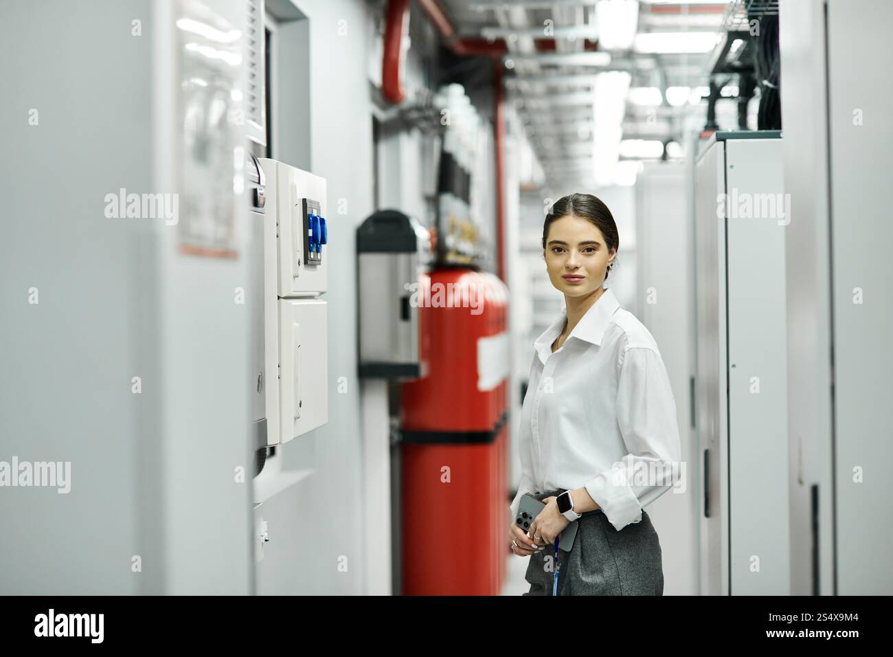Una donna dedicata in camicia bianca gestisce abilmente l'hardware dei server in un data center. Foto Stock