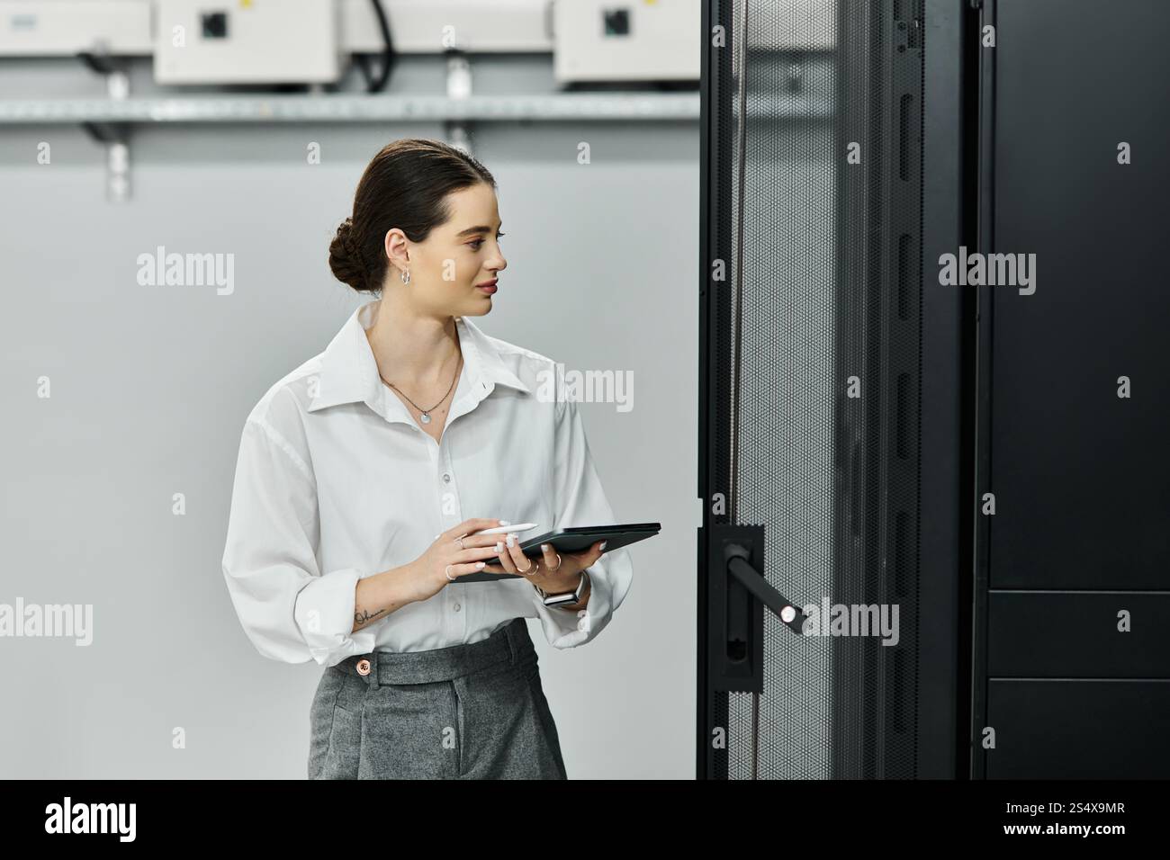 Uno specialista IT specializzato lavora diligentemente in una sala server moderna, monitorando i sistemi. Foto Stock