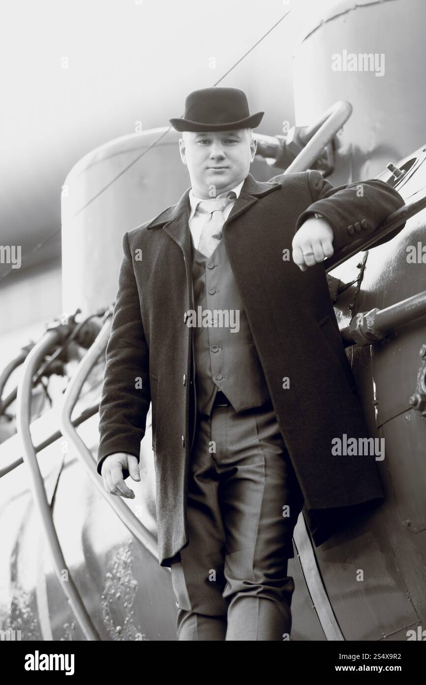 Bianco e nero ritratto di uomo in cappello bowler permanente sulla vecchia locomotiva Foto Stock