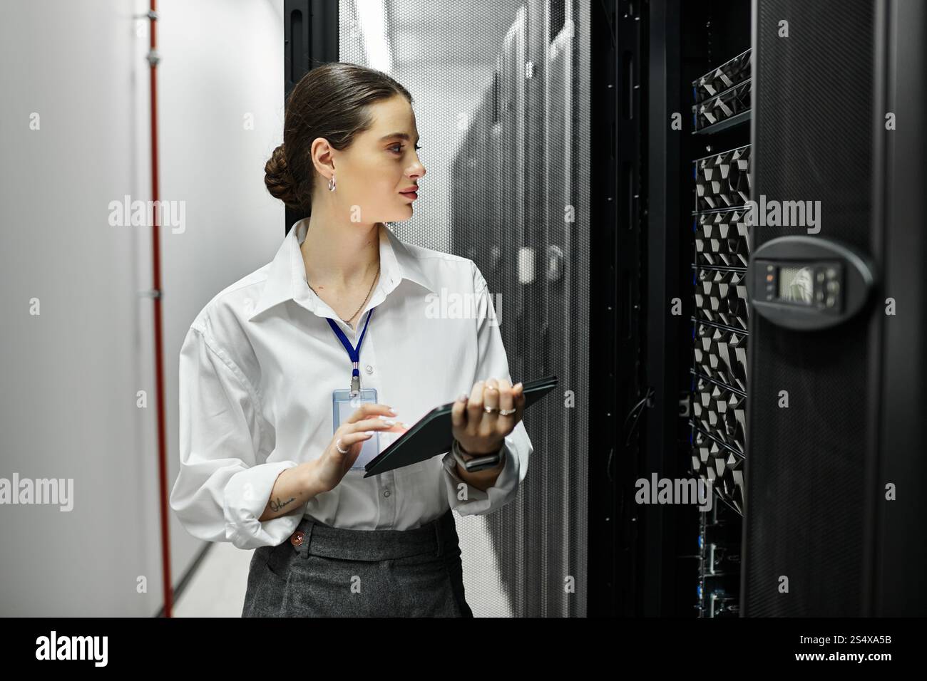 Uno specialista IT in una camicia bianca gestisce le apparecchiature di un data center monitorando al contempo le prestazioni. Foto Stock