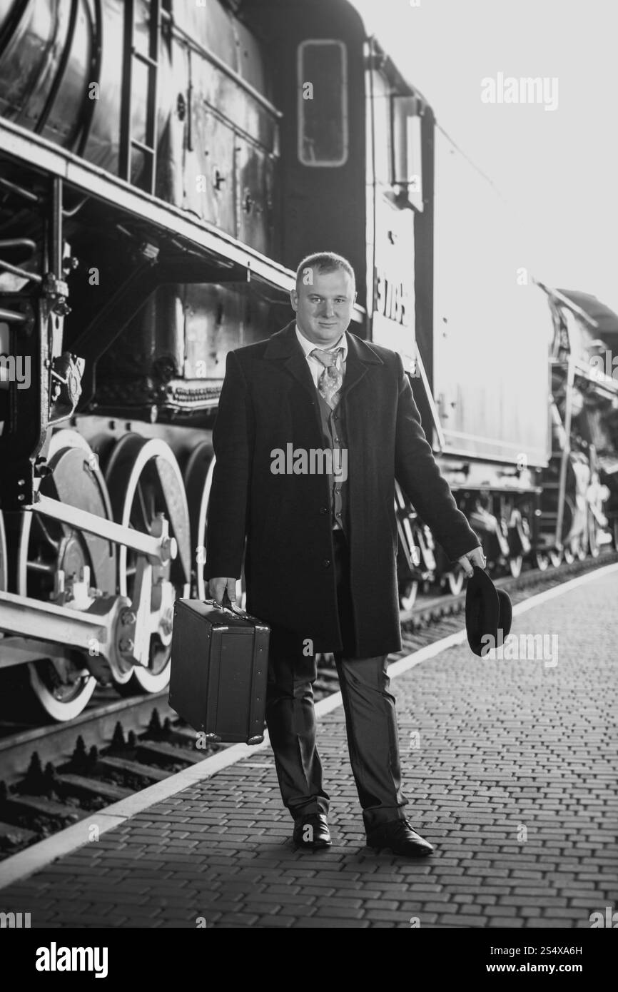 Bianco e nero Photo retrò di uomo bello in tuta in attesa del treno Foto Stock