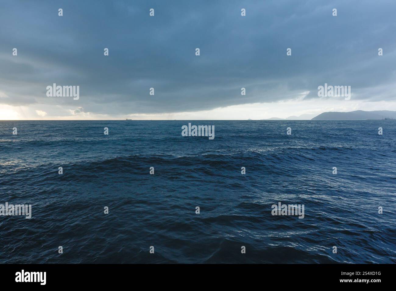 La sera nuvoloso mare e navi all'orizzonte Foto Stock