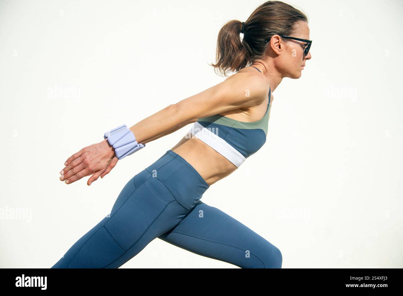 donna che indossa pesi regolabili che fanno pilates Foto Stock