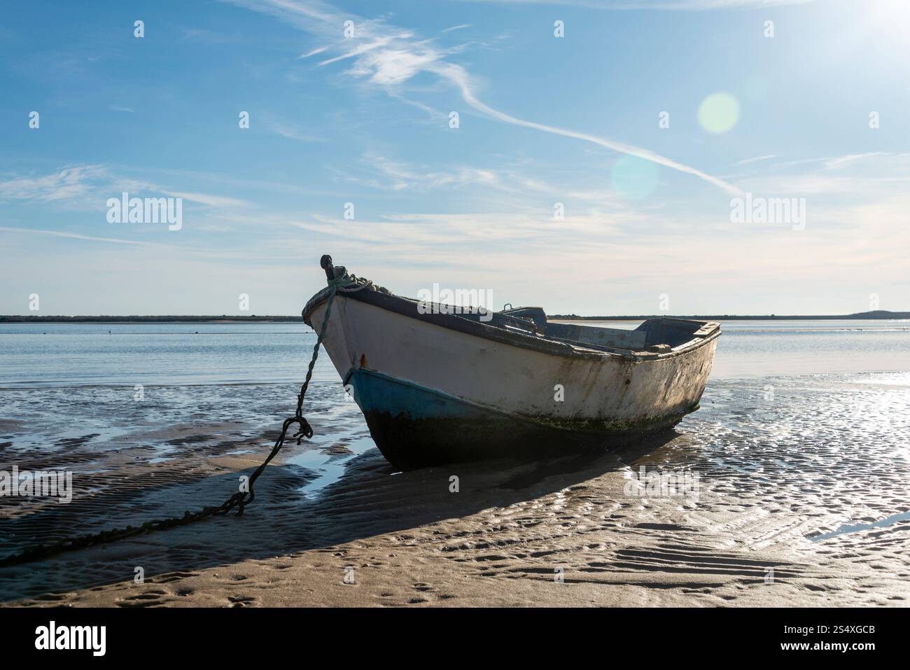 vecchia barca di legno seduta su una spiaggia con bassa marea Foto Stock