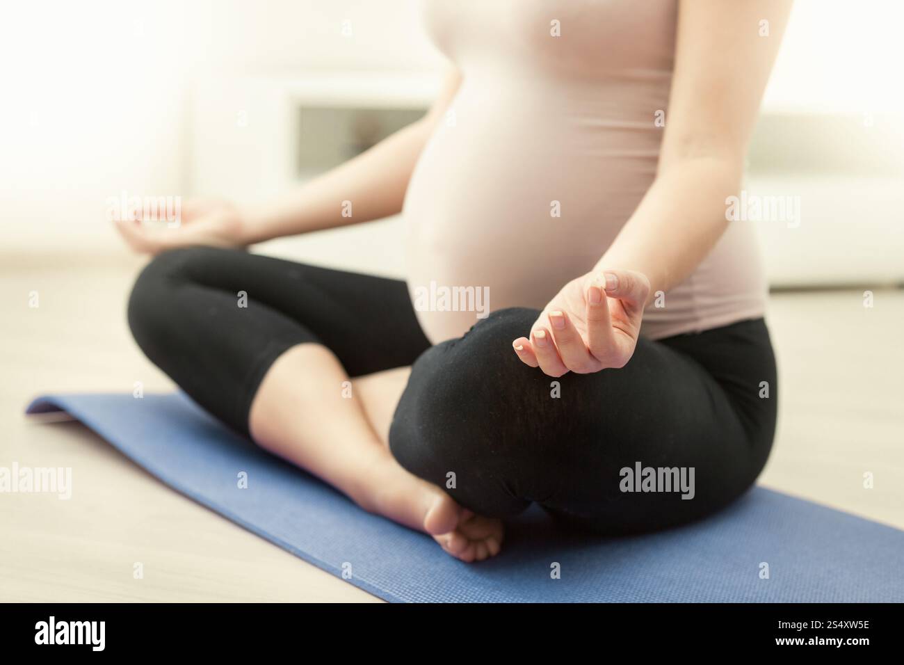 Primo piano della donna incinta a praticare yoga a casa Foto Stock