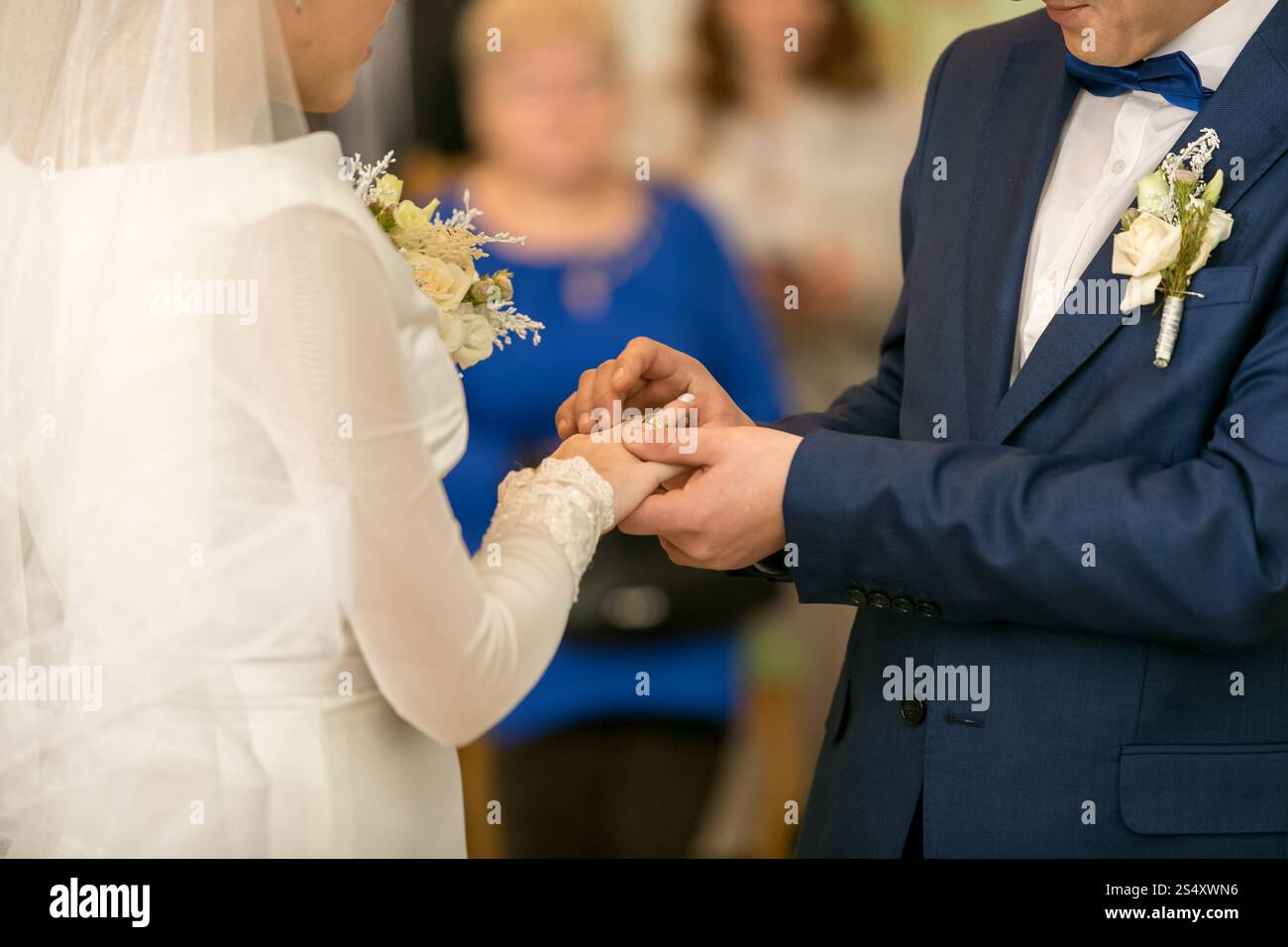 Primo piano del giovane sposo di mettere l'anello nuziale sulla sposa del dito Foto Stock