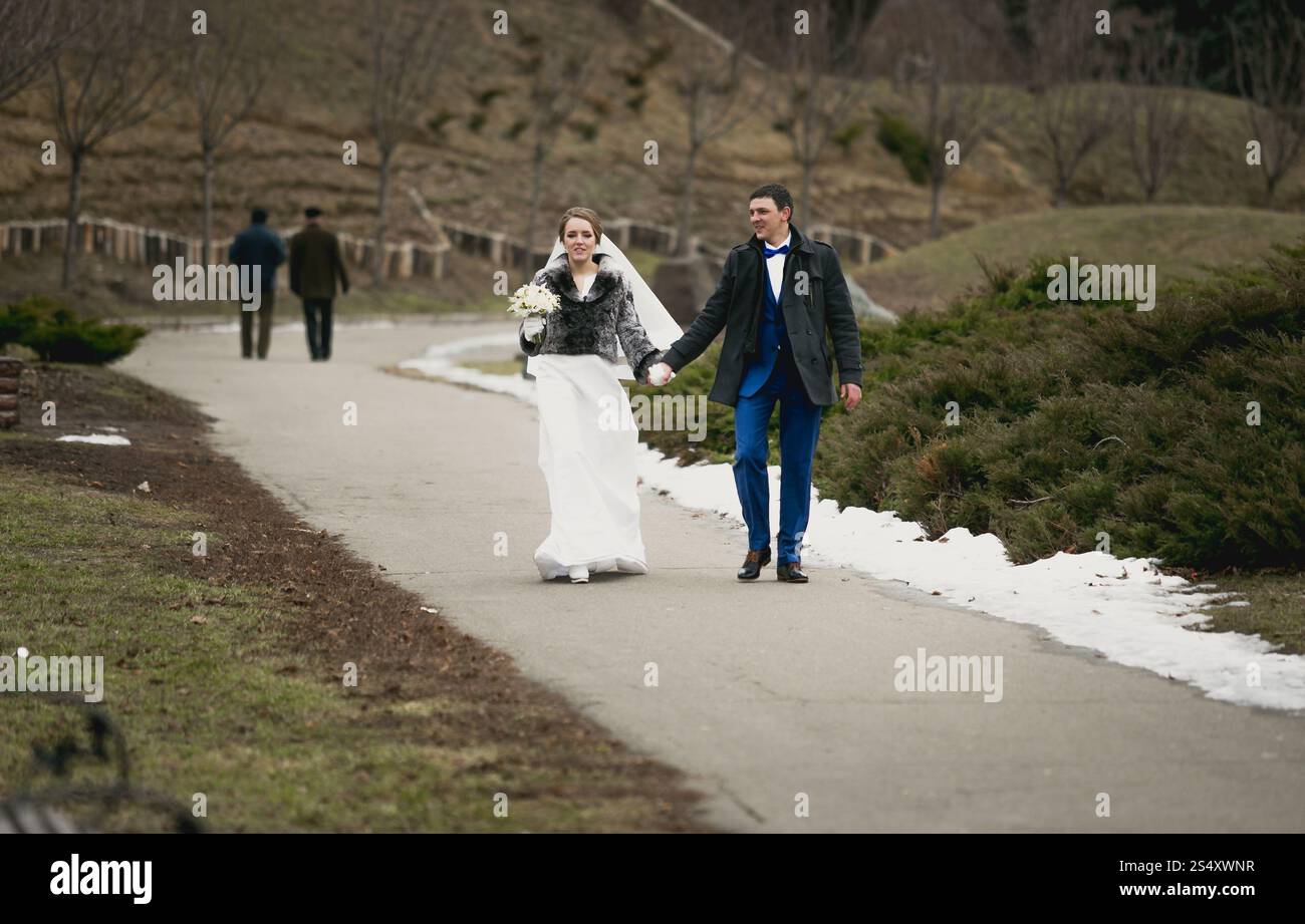 Happy sposi novelli a camminare sulla strada a winter park Foto Stock