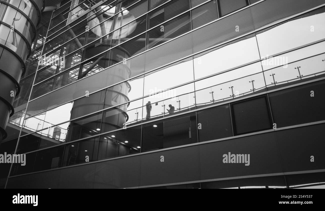 Immagine in bianco e nero di persone che riflette nel moderno edificio di vetro Foto Stock